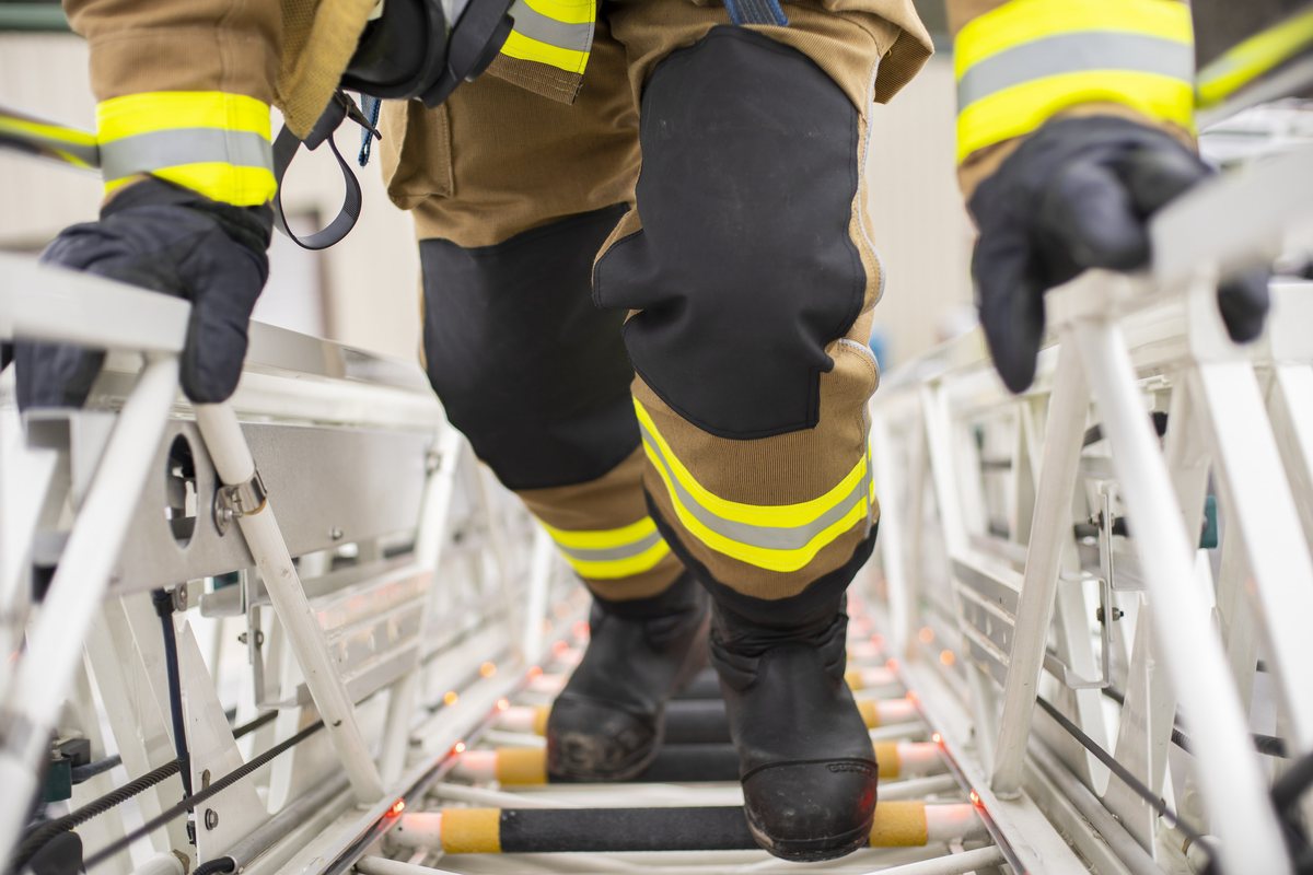 Firefighter climbing a ladder, reinforced knees on the turnout pants in frame